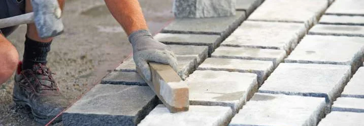 Person verlegt Pflastersteine